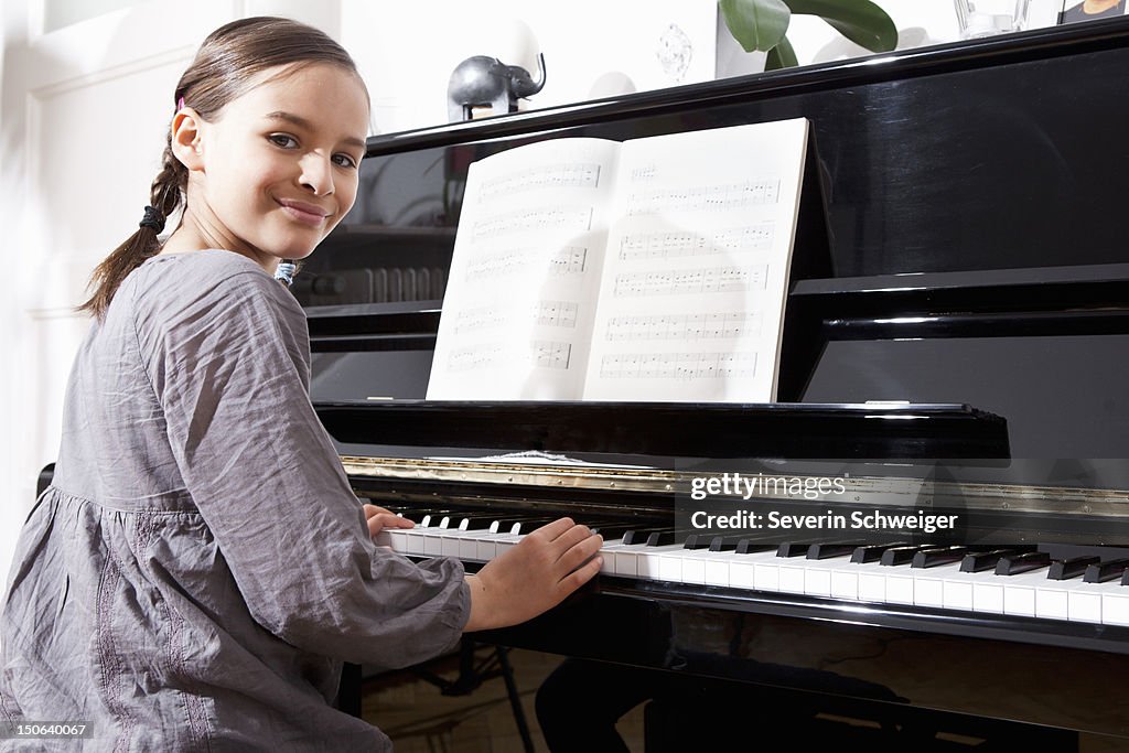 Smiling girl practicing at piano