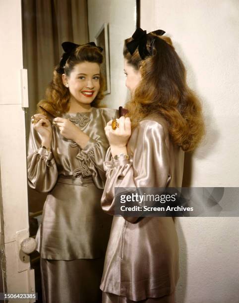 American actress Gloria DeHaven wearing a silk outfit in front of a mirror, circa 1944.
