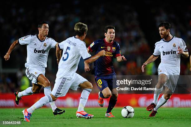 Lionel Messi of FC Barcelona duels for the ball with Cristiano Ronaldo, Fabio Coentrao and Xabi Alonso of Real Madrid CF during the Super Cup first...