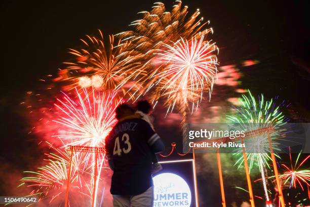 Carlos Hernandez of the Kansas City Royals holds one of his children as fireworks are set off after the Los Angeles Dodgers defeat the Kansas City...