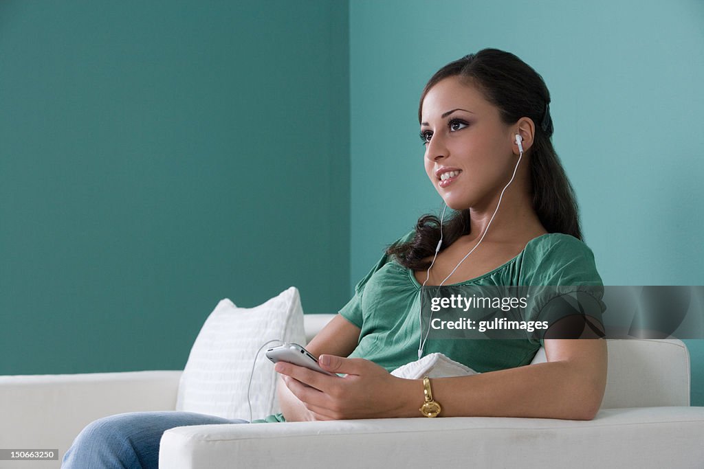 Young woman with earphone, sitting on a sofa