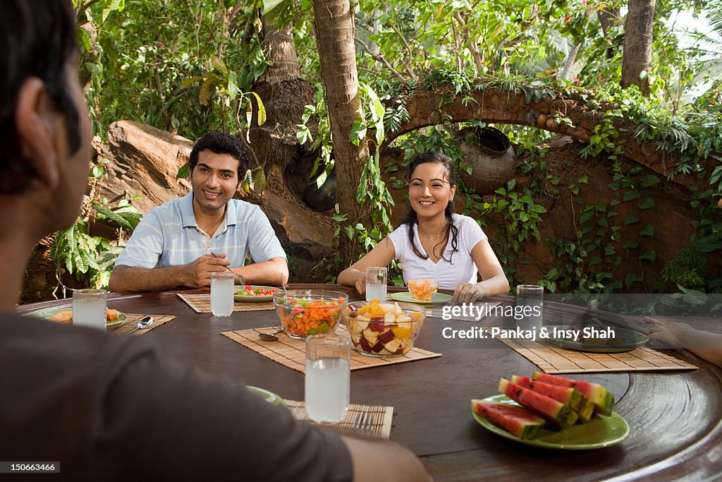 Friends sitting outdoor, table talking and smiling