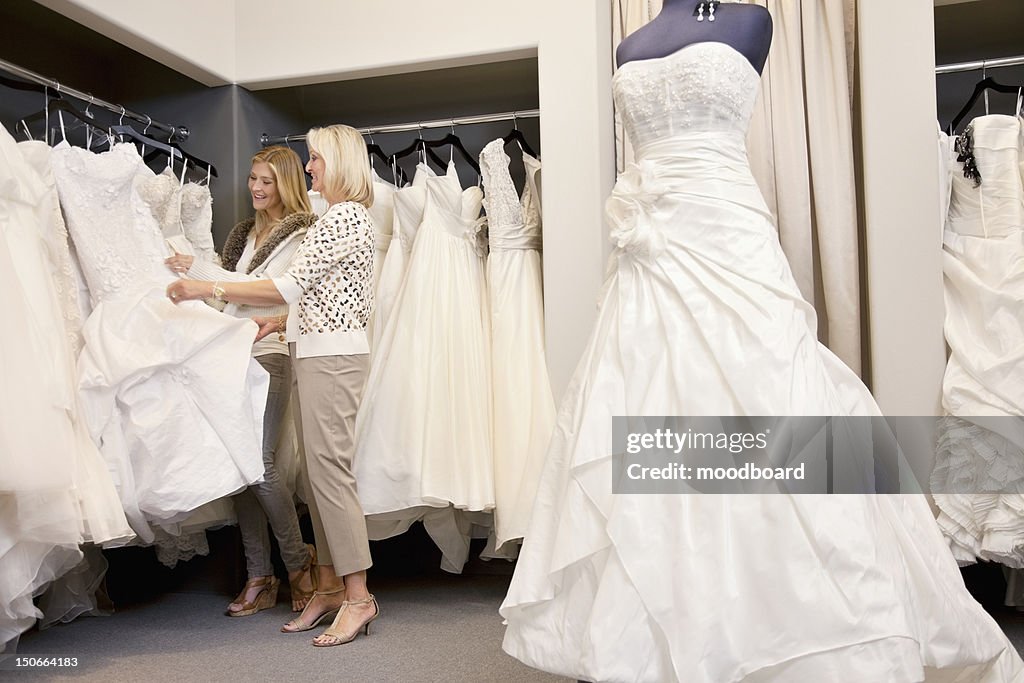 Happy mother and daughter shopping together for wedding gown in boutique