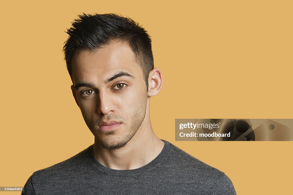 Portrait of a confident young man over colored background