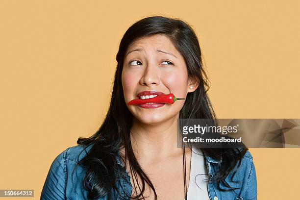 young woman with red chili pepper in mouth over colored background - female eating chili bildbanksfoton och bilder