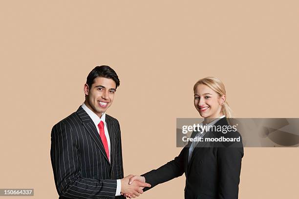 portrait of young business people shaking hands over colored background - handshake isolated stock pictures, royalty-free photos & images