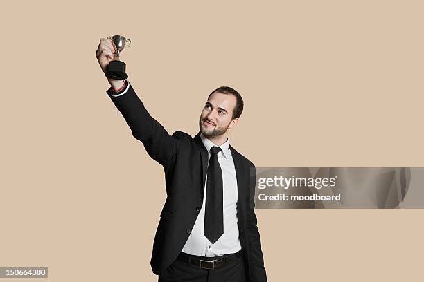 happy young man raising winning trophy over colored background - holding trophy stockfoto's en -beelden