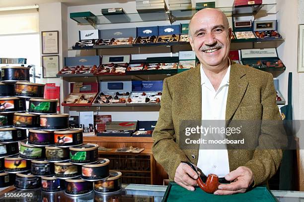 portrait of a happy mature tobacco shop owner with cans on display - tobacconists stock pictures, royalty-free photos & images