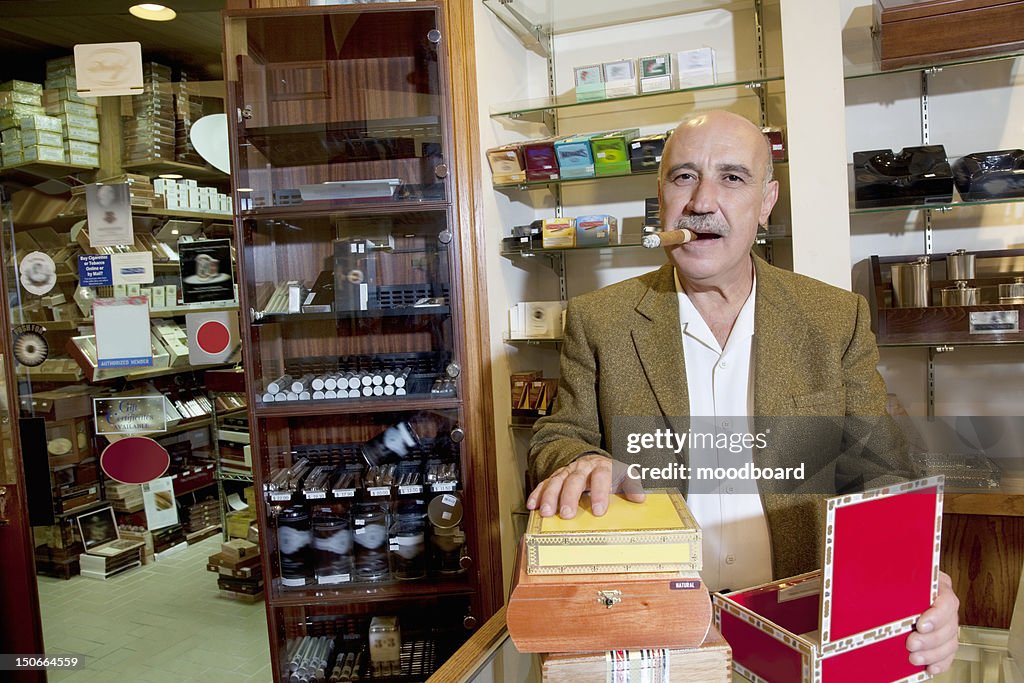 Portrait of a mature man smoking cigar with display in background
