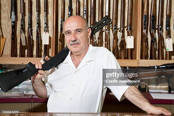 portrait of a mature man with rifle on shoulder in gun store - palm desert california stock pictures, royalty-free photos & images