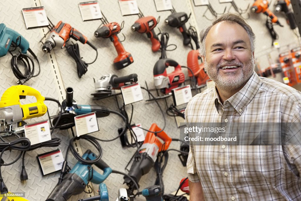 Happy mature hardware store owner looking away