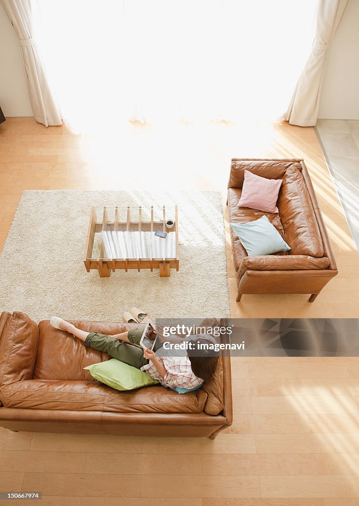 Middle-aged woman using a tablet PC on a sofa