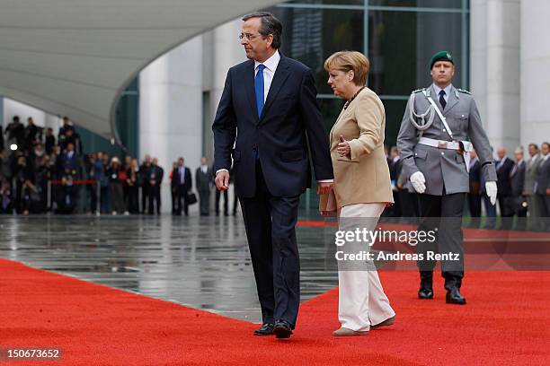 German Chancellor Angela Merkel and Greek Prime Minister Antonis Samaras review a guard of honour upon Samaras arrival at the Chancellery on August...