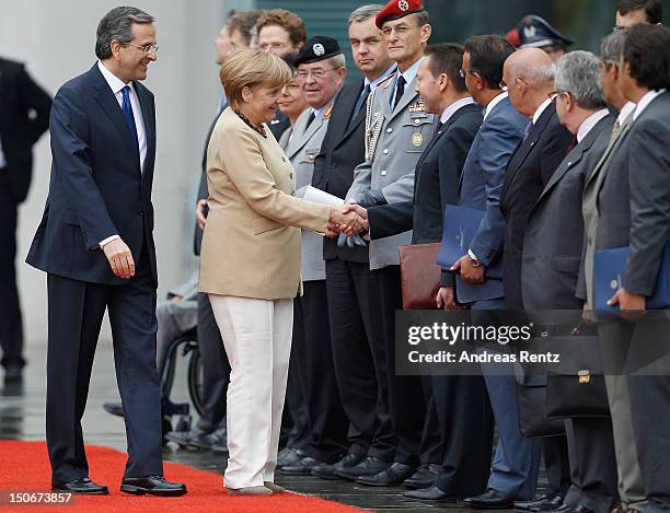 German Chancellor Angela Merkel shakes hands with Greek Finance Minister Yannis Stournaras as Greek Prime Minister Antonis Samaras smiles upon...