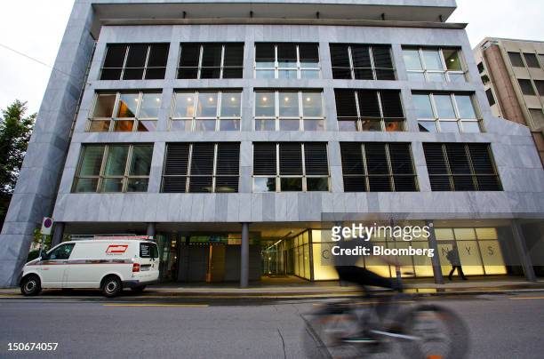 Cyclists rides past the building that houses the headquarters of Xstrata Plc in Zug, Switzerland, on Friday, Aug. 24, 2012. Glencore's planned...