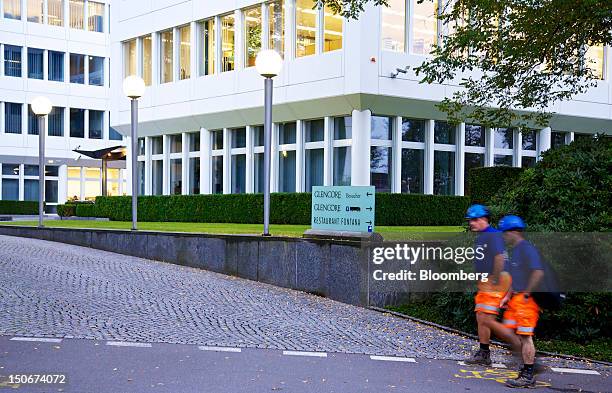 Workmen walk past the entrance to Glencore International Plc's headquarters in Baar, Switzerland, on Friday, Aug. 24, 2012. Glencore's planned...