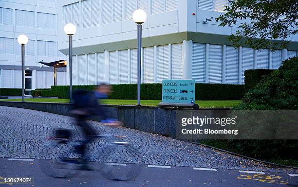 Cyclist passes the entrance to Glencore International Plc's headquarters in Baar, Switzerland, on Friday, Aug. 24, 2012. Glencore's planned takeover...