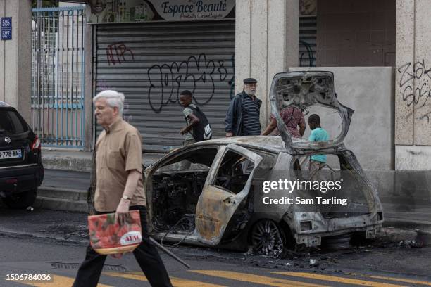 The scorched remains of a car remain by the side of a major roadway follwing a fourth night of unrest on the outskirts of Paris, on July 1, 2023 in...