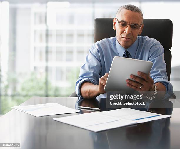 businessman looking over electronic tablet - e reader stock pictures, royalty-free photos & images
