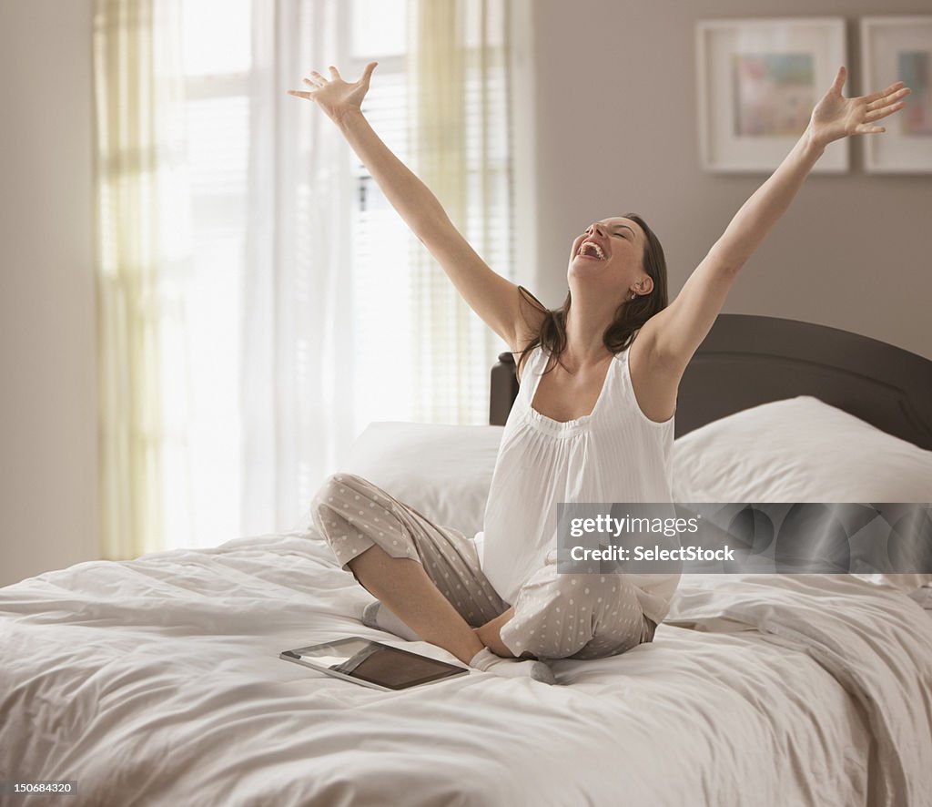 Woman with arms raised in bed