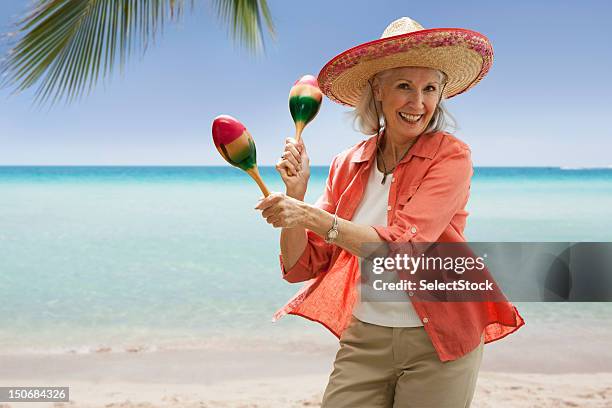 senior mujer en la playa con maracas - maracas fotografías e imágenes de stock