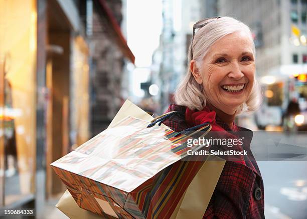 senior frau holding einkaufstaschen - christmas newyork stock-fotos und bilder