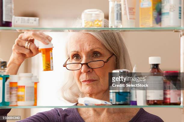 senior woman looking at prescription bottles - prescription medicine stock pictures, royalty-free photos & images