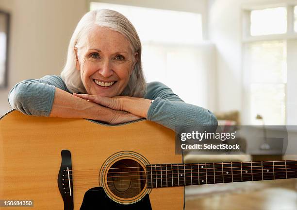 senior frau mit gitarre - saiteninstrument spielen stock-fotos und bilder