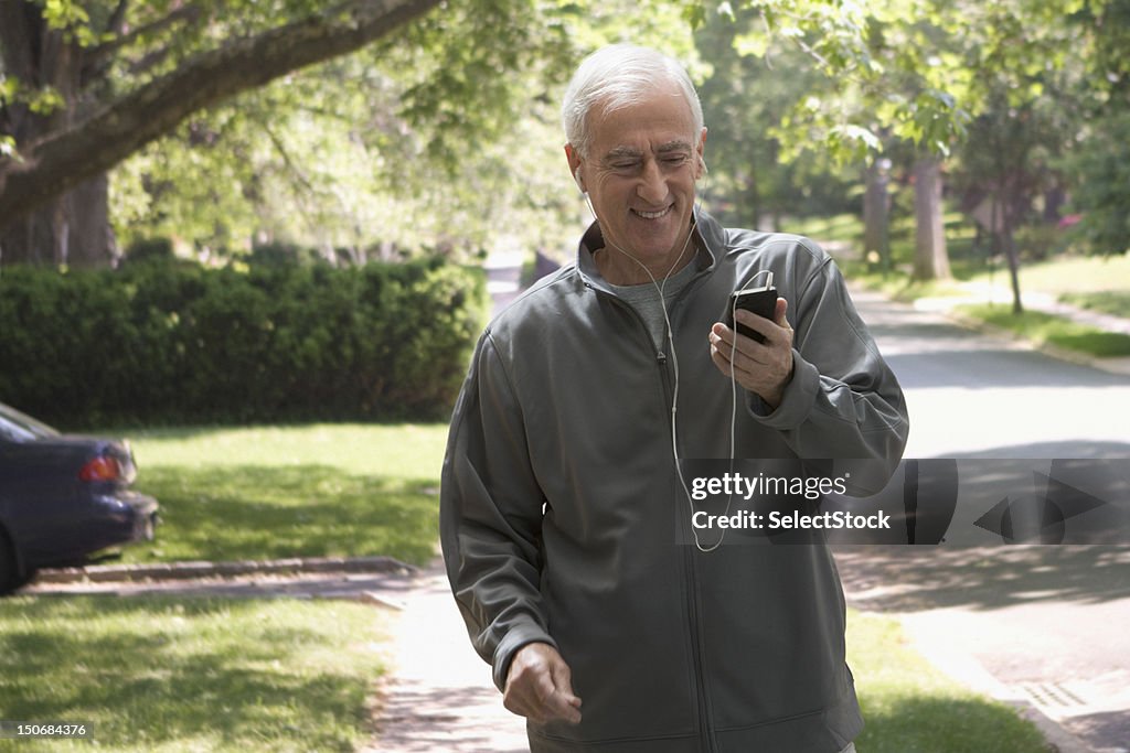 Senior man checking mp3 player outdoors