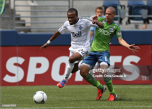 Dane Richards of the Vancouver Whitecaps dribbles against Osvaldo Alonso of the Seattle Sounders FC at CenturyLink Field on August 18, 2012 in...