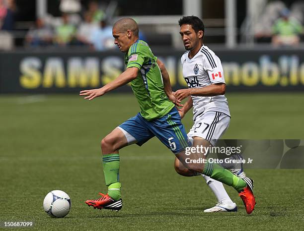 Osvaldo Alonso of the Seattle Sounders FC dribbles against Jun Marques Davidson of the Vancouver Whitecaps at CenturyLink Field on August 18, 2012 in...