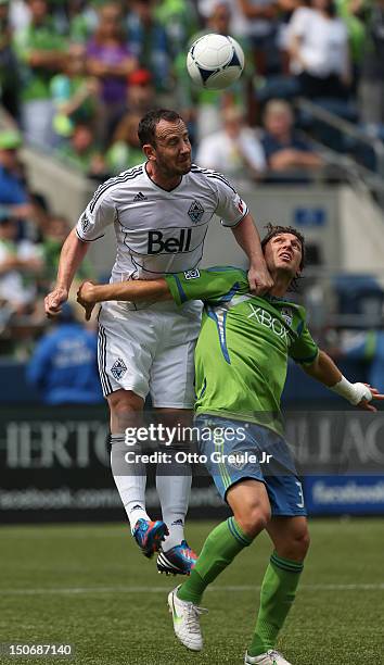 Andy O'Brien of the Vancouver Whitecaps heads the ball against Jeff Parke of the Seattle Sounders FC at CenturyLink Field on August 18, 2012 in...