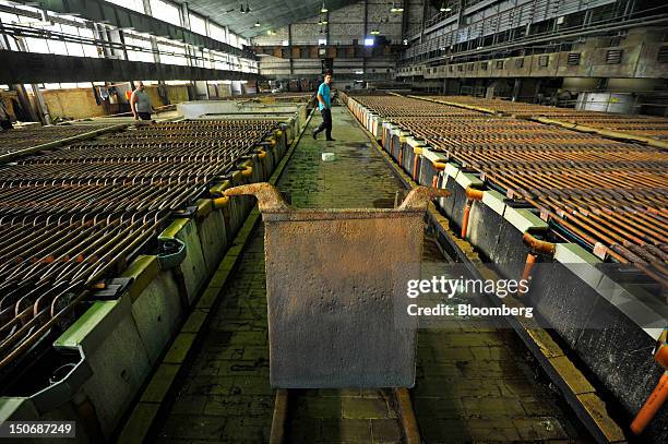 Workers move between electrolytic tanks containing copper cathode sheets in the electrolytic refining plant, or tankhouse, at the copper mining and...