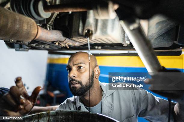 mechaniker wechselt autoöl in einer autowerkstatt - ölwechsel stock-fotos und bilder