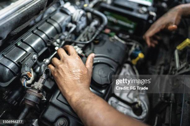 mains d’un mécanicien réparant une voiture dans un atelier de réparation automobile - moteur photos et images de collection