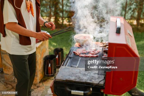 homem cozinhando salsicha na churrasqueira, atividades de fim de semana no quintal - casa de jardim ou parque - fotografias e filmes do acervo