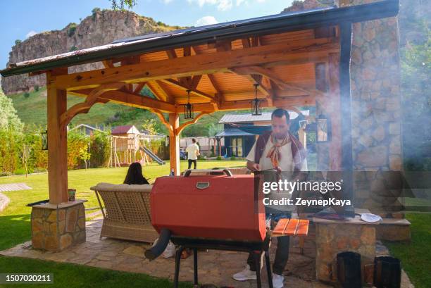 hombre cocinando barbacoa en la parrilla, actividades de fin de semana en el patio trasero - cenador fotografías e imágenes de stock