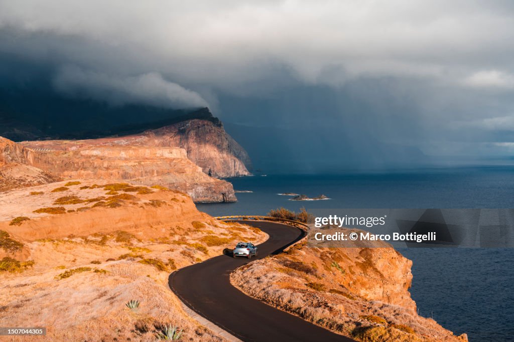 Car driving on winding coastal road, Madeira island, Portugal