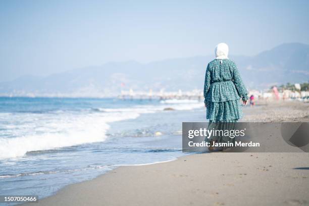 muslim woman walking on beach alone - arabic literature stock pictures, royalty-free photos & images