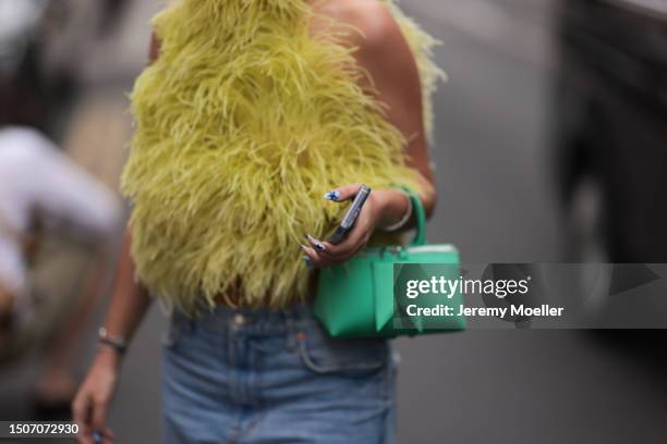 Payly is seen wearing black Prada shades, a yellow feather-top, a green bag, prada heels and a jeans outside during the Bluemarble Menswear...