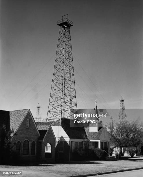 An oil derrick in a churchyard rises above the church building in Oklahoma City, Oklahoma, circa 1955.