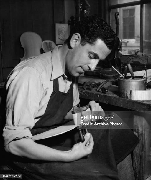 British-German luthier Ernst Voight glues the sycamore ribs of a violin, fastening them to the back with a clamp at the Voight workshop in Soho,...