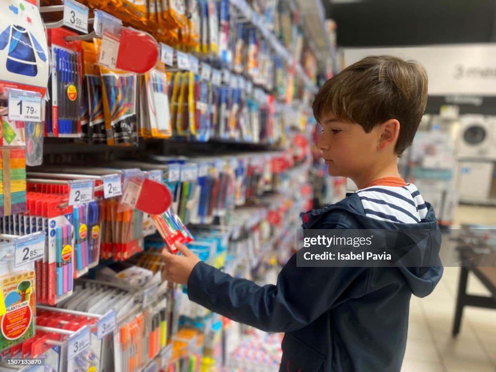 Boy looking for back to school stationery in a store
