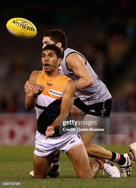 Curtly Hampton of the Giants handballs whilst being tackled by Leigh Montagna of the Saints during the round 22 AFL match between the St Kilda Saints...