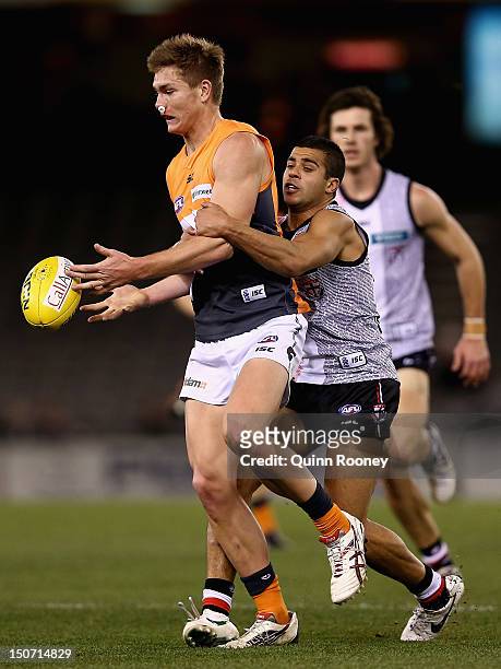 Adam Tomlinson of the Giants is tackled by Ahmed Saad of the Saints during the round 22 AFL match between the St Kilda Saints and the Greater Western...