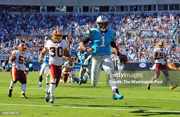 Carolina Panthers quarterback Cam Newton carries the ball past Washington Redskins inside linebacker London Fletcher and Washington Redskins strong...