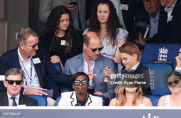 Prince William, Prince of Wales and Prince George of Wales hold a replica Ashes Urn while sitting next to Richard Thompson, Chairman of the...