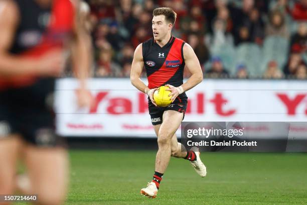 Zach Merrett of the Bombers runs with the ball during the round 16 AFL match between Essendon Bombers and Port Adelaide Power at Melbourne Cricket...