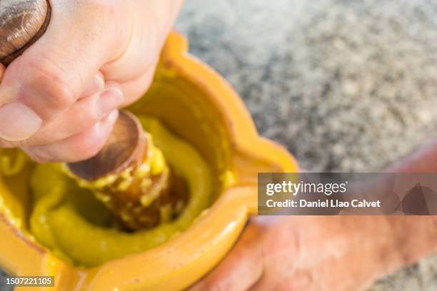 hands of a man making aioli with olive oil and garlic in a mortar. - aioli stock pictures, royalty-free photos & images