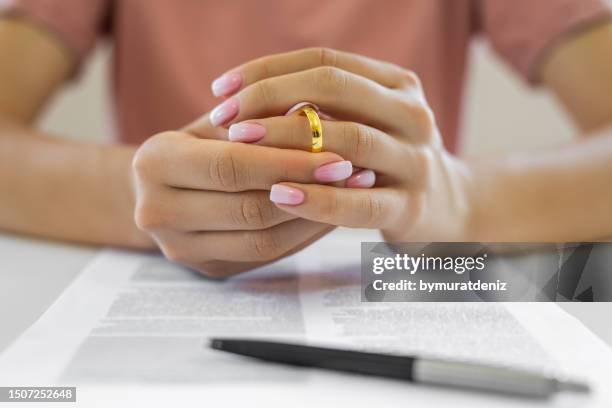 female hands removing wedding ring - marriage annulment stock pictures, royalty-free photos & images